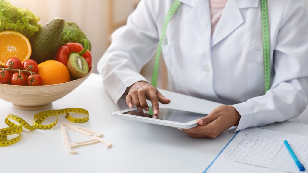 Obrazek przedstawia dietetyczkę sprawdzającą coś na tablecie