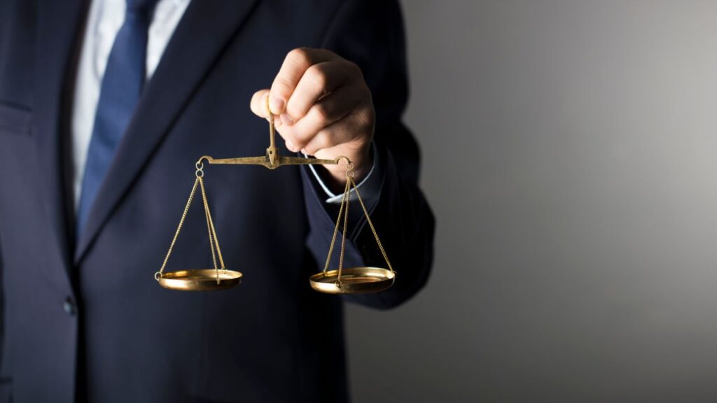 Obrazek przedstawia prawnika, który trzyma wagę